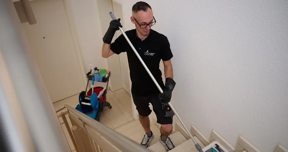 Eine Reinigungsfachkraft der Firma Immobilienservice Mauss bei der gewerblichen Treppenhausreinigung. Putzkraft putzt und reinigt Treppenhaus mit einem Mob und speziellen Reinigungsmitteln.