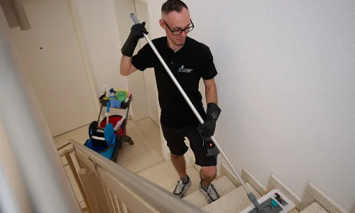 Eine Reinigungsfachkraft der Firma Immobilienservice Mauss bei der gewerblichen Treppenhausreinigung. Putzkraft putzt und reinigt Treppenhaus mit einem Mob und speziellen Reinigungsmitteln.