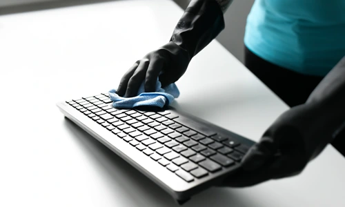 Reinigungskraft von Immobilien Service Mauss bei der hygienischen Reinigung einer Computertastatur – gründliche Unterhaltsreinigung für saubere und produktive Arbeitsplätze.